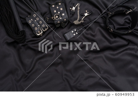 Leather handcuffs, black whip, chain collar and stack on black background. Accessories for adult sexual game. BDSM outfit. 60949953