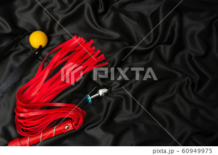 Red whip, gag, anal plug on a black silk 60949975