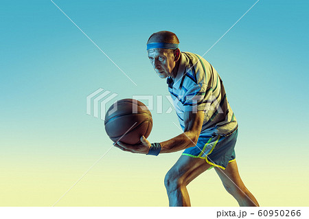 Senior man playing basketball in sportwear on gradient background and neon light Senior man playing basketball in sportwear on gradient background and neon light 60950266