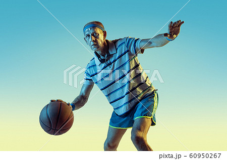 Senior man playing basketball in sportwear on gradient background and neon light Senior man playing basketball in sportwear on gradient background and neon light 60950267