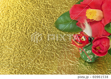 冬のバラとも呼ばれるツバキの花と金箔の紙の上に立つ獅子舞の可愛いフィギュアのグリーティングカード。 60961538