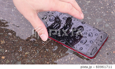 雨の日の道路に落ちたスマートフォンを拾う 雨の日の道路に落ちたスマートフォンを拾う 60961711