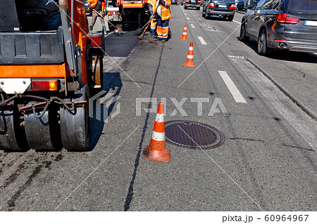 Road orange cones enclose the work crew and road 60964967