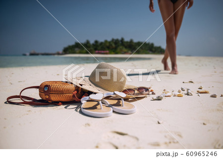 female legs on white beach with travel accessories, exotic vacation, product photo for travel agency 60965246