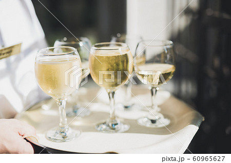 Waiter serving glasses with champagne on a tray Waiter serving glasses with champagne on a tray 60965627