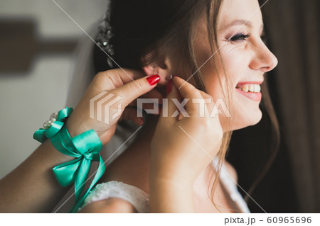 Luxury bride in white dress posing while preparing for the wedding ceremony Luxury bride in white dress posing while preparing for the wedding ceremony 60965696