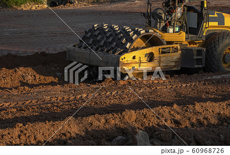 Soil compactor with vibratory padfoot drum. Heavy duty machinery working on highway construction site. Vehicle for soil compaction. Road construction equipment. Paving. Compaction of the road. 60968726