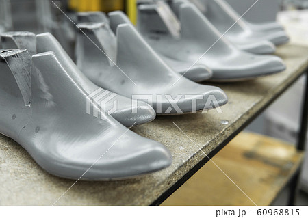 Plastic lasts used in the manufacture of shoes. Row of plastic shoe lasts used to manufacture modern day shoes. A lot of plastic last shoe on a wooden shelf. The equipment used for shoe design. Plastic lasts used in the manufacture of shoes. Row of plastic shoe lasts used to manufacture modern day shoes. A lot of plastic last shoe on a wooden shelf. The equipment used for shoe design. 60968815