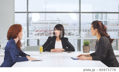 Determined business partners actively studying business documents at wooden conference table Determined business partners actively studying business documents at wooden conference table 60973776