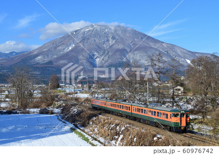 新雪の黒姫山をバックに走る湘南色しなの鉄道115系電車 60976742