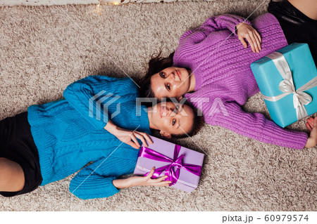 Two beautiful women with gifts at the Christmas tree garlands new year Two beautiful women with gifts at the Christmas tree garlands new year 60979574