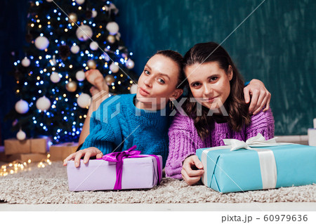 Two beautiful women with gifts at the Christmas tree garlands new year Two beautiful women with gifts at the Christmas tree garlands new year 60979636