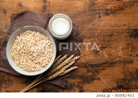 Rolled oats, oat flakes and oat milk on wooden table Rolled oats, oat flakes and oat milk on wooden table 60982401