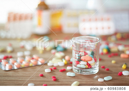 Colorful pills and medicines in the glass cup with capsule on wooden table background. 60983808