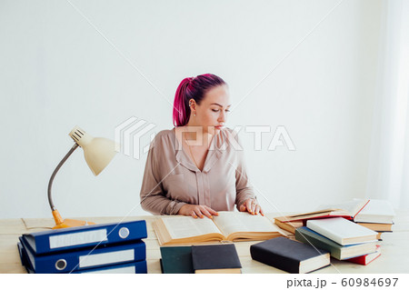 beautiful business woman working in an Office behind a table with books beautiful business woman working in an Office behind a table with books 60984697