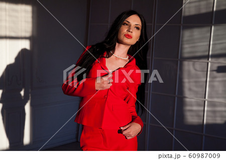 Portrait of a beautiful fashionable woman in a red business suit in the office 60987009