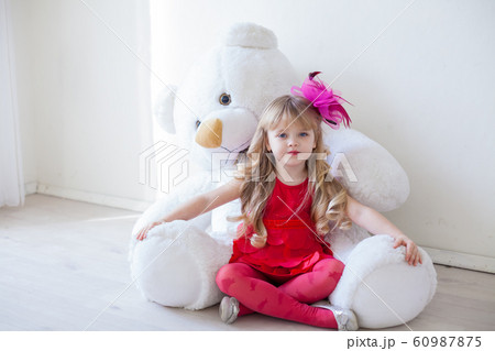 Beautiful little girl with big soft bear toy 60987875