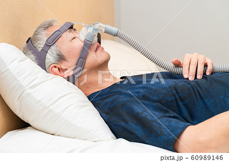 Middle age Asian man wearing CPAP headgear during his sleep 60989146