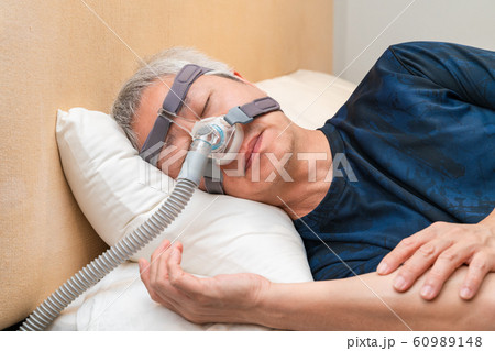 Middle age Asian man wearing CPAP headgear during his sleep 60989148