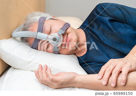 Middle age Asian man wearing CPAP headgear during his sleep 60989150