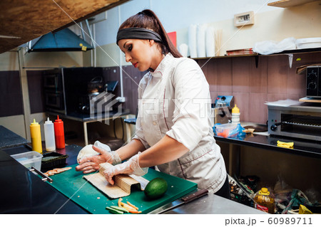 woman chef prepares fresh sushi in the kitchen of the restaurant 60989711