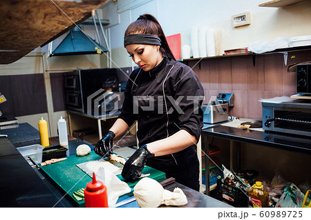 woman chef prepares fresh sushi in the kitchen of the restaurant 60989725