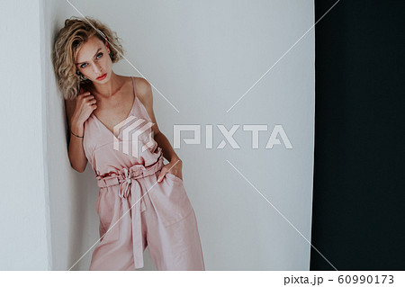 Portrait of a beautiful fashionable blonde woman in a pink jumpsuit on a black white background 60990173