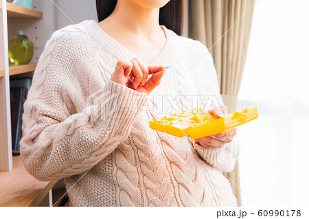 薬ケースから取り出す妊婦 60990178