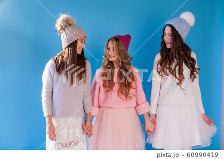 Portrait of three beautiful fashionable girls in dresses and hats in winter Portrait of three beautiful fashionable girls in dresses and hats in winter 60990419