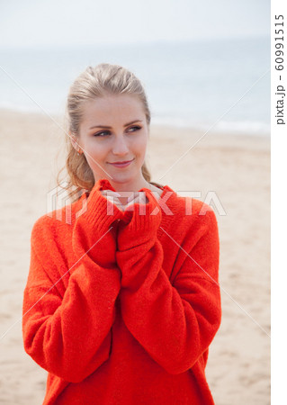 Beautiful blonde woman in walks alone on an empty beach by the sea Beautiful blonde woman in walks alone on an empty beach by the sea 60991515