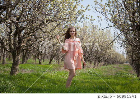 Beautiful blonde woman in pink dress in green flowering garden in spring 60991541