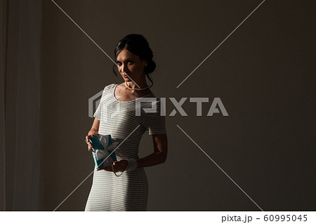 portrait of a beautiful fashionable brunette woman with a gift in her hands 60995045