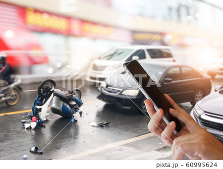 Concept of car accidents, emergency and insurance concept Dangerous traffic on the road, Careless driving car collides with motorcycle. Woman hands using smartphone calling ambulance and car insuranc 60995624