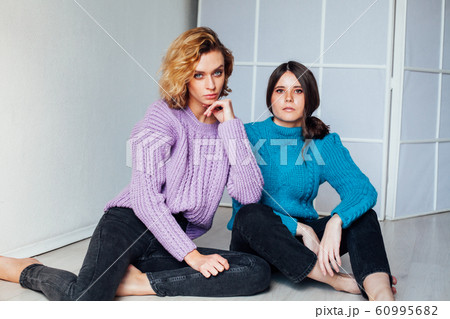 Portrait of two beautiful fashionable blonde women and a brunette in a winter sweater 60995682