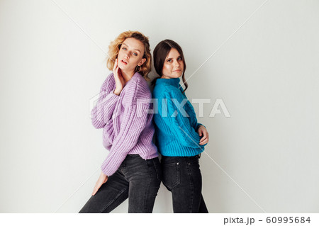 Portrait of two beautiful fashionable blonde women and a brunette in a winter sweater 60995684