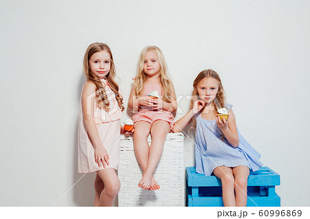 three little girls eat sweet cake with cream cupcake 60996869