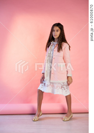 Portrait of a beautiful fashionable girl in a pink jacket and white dress 61000870