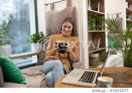 Smiling photographer editing her pictures in photoshop 61001075