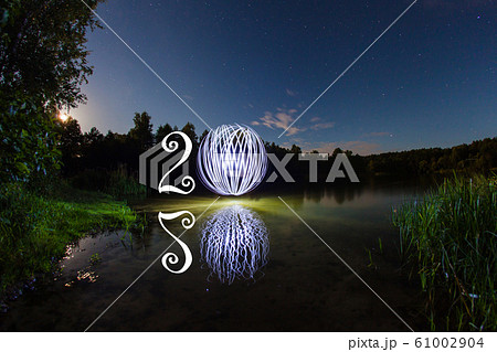 2020 written on the air with glowing ball mirrored on surface of water 2020 written on the air with glowing ball mirrored on surface of water 61002904
