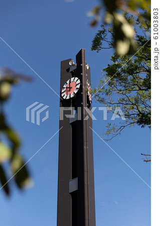 国会前 憲政記念公園の時計塔 （赤と白の文字盤部分をアップに見る、縦位置、青空バック、立木越し） 61003803