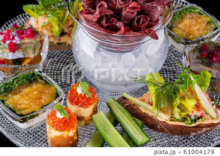 Slugged meat in ice, pancakes with red caviar, fish snack on glass tray Slugged meat in ice, pancakes with red caviar, fish snack on glass tray 61004178