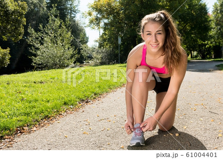 young woman runner tying her shoes preparing for a young woman runner tying her shoes preparing for a 61004401