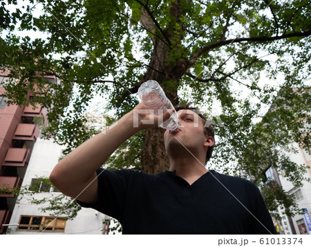 A man drinking water from a plastic bottle 61013374