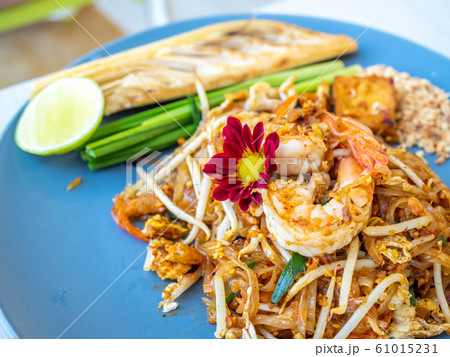 Pad thai, stir fried rice noodle with shrimp in Thai style, one of the most favorite well known Thailand street food, served with lemon, garlic chives and banana flowers 61015231
