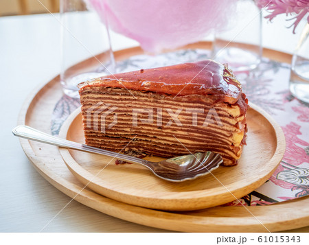 A piece of strawberry jam crepe cake on wooden round plate 61015343