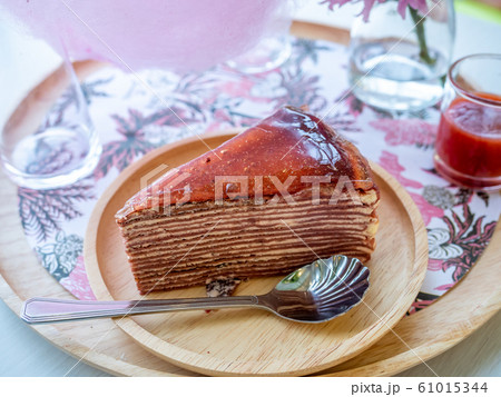 A piece of strawberry jam crepe cake on wooden round plate 61015344