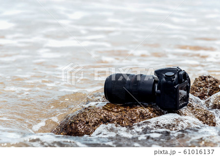 DSLR camera on stone beach wet from water sea wave DSLR camera on stone beach wet from water sea wave 61016137