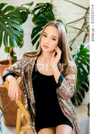 Teenager girl with long hair in a black dress and a sparkling jacket among tropical plants in tudia. Evening fashion Teenager girl with long hair in a black dress and a sparkling jacket among tropical plants in tudia. Evening fashion 61020714