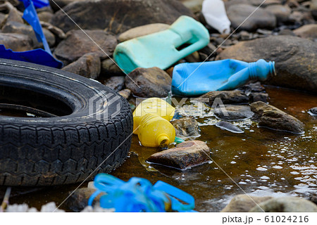 Enviromental pollution. Rubber tire with plastic waste in dirty water. Enviromental pollution. Rubber tire with plastic waste in dirty water. 61024216