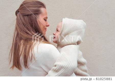 Woman mom holds child in her arms, little boy son, autumn and winter, warm casual clothes, beige wall background. Happy smiling have rest weekend. Emotions of love care and support. Woman mom holds child in her arms, little boy son, autumn and winter, warm casual clothes, beige wall background. Happy smiling have rest weekend. Emotions of love care and support. 61025881